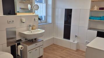 Une salle de bain moderne avec des toilettes, un lavabo, un miroir et un tapis bleu.
