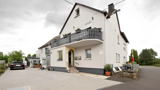 A two-story house with a balcony, a driveway, and a street view.
