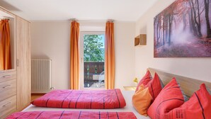 A bedroom with a bed, curtains, a radiator, a window, and a painting. - Room 'Rienznerhof Fernblick No. 4' with Mountain View, Shared Terrace & Wi-Fi (Montan an der Weinstraße)