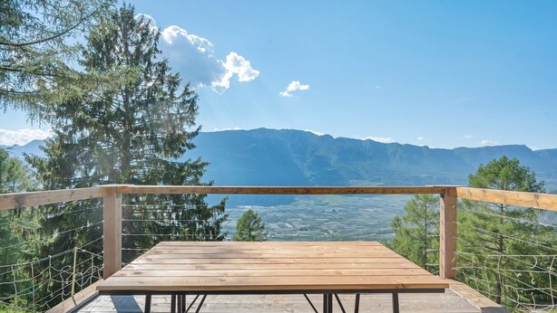 A wooden deck with a table and railing overlooking a mountainous landscape. - Room 'Rienznerhof Fernblick No. 4' with Mountain View, Shared Terrace & Wi-Fi (Montan an der Weinstraße)