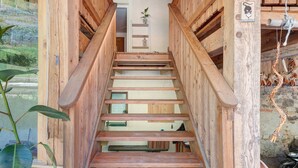 A wooden staircase leading to a room with a plant, a shelf, and a motorcycle outside. - Room 'Rienznerhof Fernblick No. 4' with Mountain View, Shared Terrace & Wi-Fi (Montan an der Weinstraße)