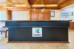 Ein Empfangsbereich mit einem 'treebo'-Logo, Holzvertäfelung, einem gerahmten Zertifikat und einem Schild mit der Aufschrift 'IT'S ALWAYS A GOOD DAY AT treebo'.