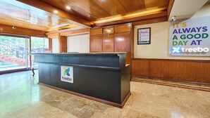 A reception desk with a 'treebo' sign, wooden paneling, a marble floor, and a 'It's always a good day at treebo' sign. - Treebo Vice President (Ahmedabad)