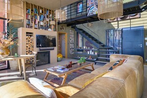 Ein modernes Wohnzimmer mit Kamin, Bücherregalen, einer Couch und einer Treppe.