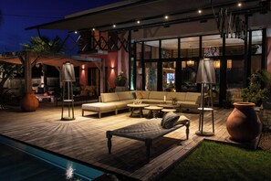 Ein moderner Außenbereich mit Pool, Holzterrasse und Gartenmöbeln.