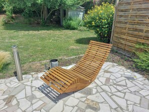 A wooden bench on a stone patio with a metal trash can nearby. - Renovated house in Courteuil near Chantilly (Courteuil)