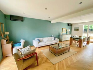 A living room with a sofa, a coffee table, a dining table with chairs, a TV, and a window with a view. - Renovated house in Courteuil near Chantilly (Courteuil)