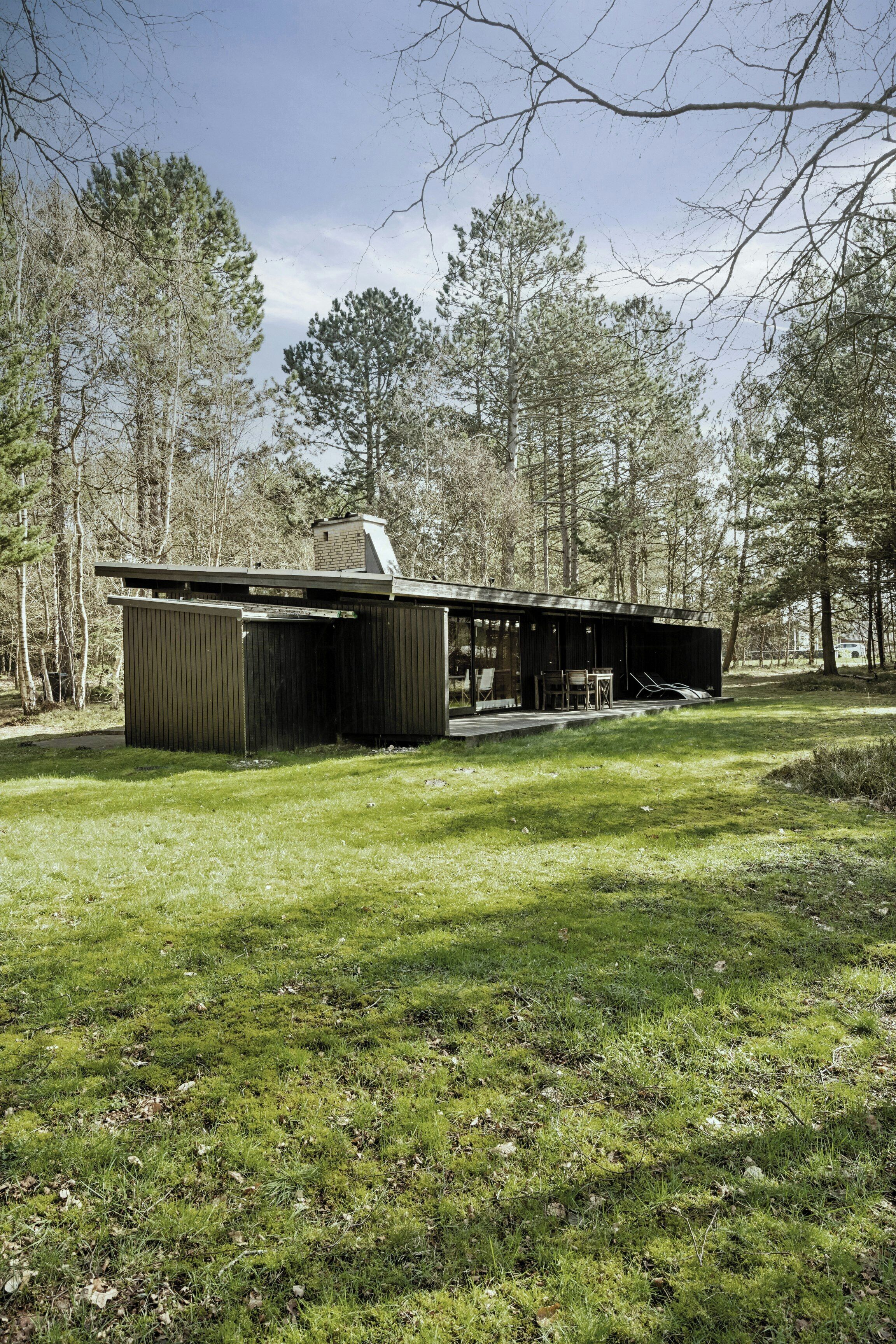Un bâtiment moderne, de plain-pied, doté d’un toit plat et entouré d’une zone herbeuse et d’arbres.