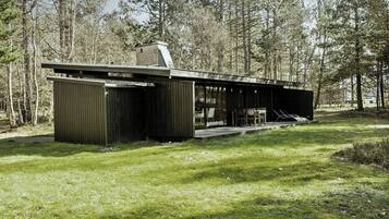 Un bâtiment moderne, de plain-pied, doté d’un toit plat et entouré d’une zone herbeuse et d’arbres.