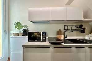 Eine moderne Küche mit Mikrowelle, Induktionskochfeld und Spüle.