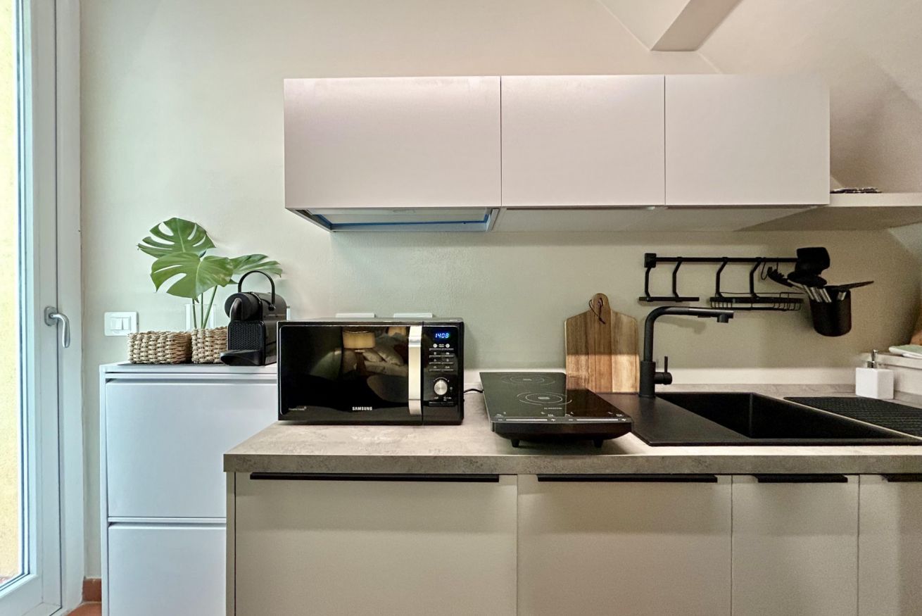 A modern kitchen with a microwave, induction cooktop, and a sink.