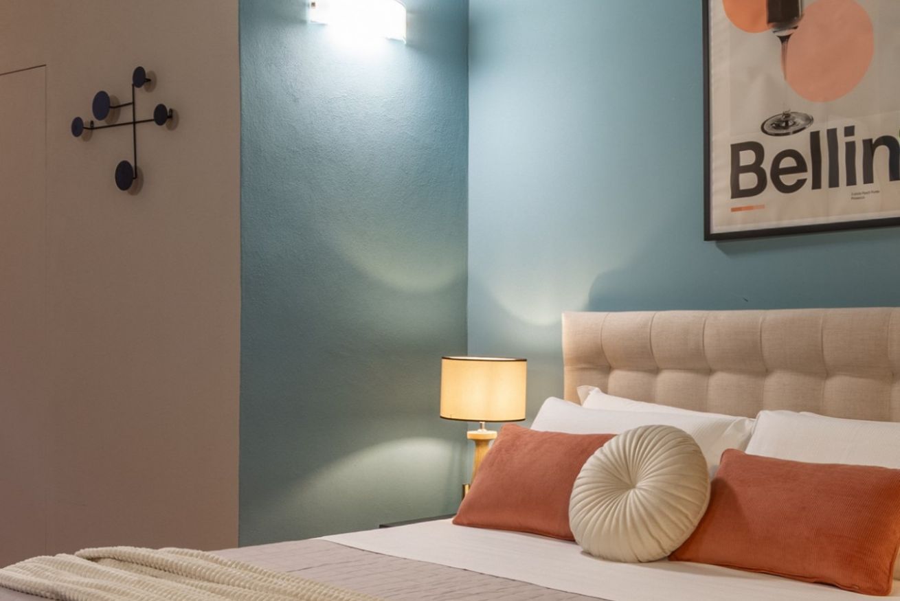 Ein Schlafzimmer mit Bett, Kissen, einer Lampe und einer Wandleuchte.
