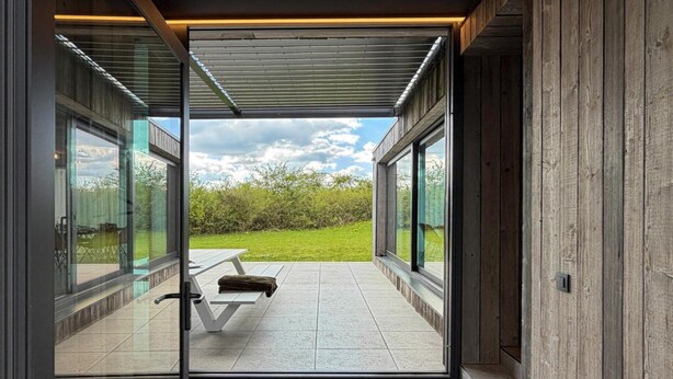 Ein modernes Interieur mit großen Glasüren, die zu einer Terrasse im Freien führen.
