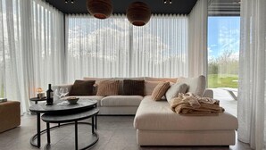 Ein modernes Wohnzimmer mit einer Couch, einem runden Couchtisch und Blick ins Freie.
