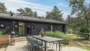 Una casa moderna con terraza, asientos exteriores y una parrilla.
