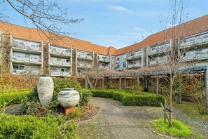 Ein Innenhof mit einem gepflasterten Weg, zwei großen Vasen und einem Gebäude mit mehreren Balkonen.