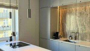 Una cuina moderna amb una illa central, electrodomèstics integrats i un gran finestral.