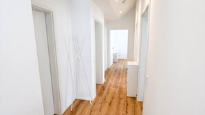 A long, narrow hallway with wooden flooring and white walls.