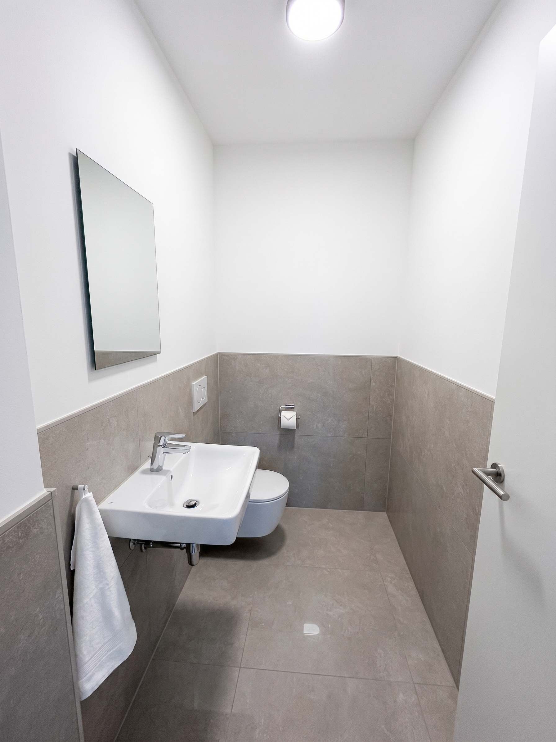 Une salle de bain avec un lavabo blanc, des toilettes et un miroir au mur.