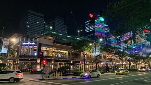 A street view at night with a building labeled 'UpTown Parade'. - Cozy Sunlit Lounge w/ Balcony City View Uptown BGC (Taguig)