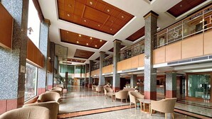 Um hall amplo com pé-direito alto, várias áreas de estar e um espaço central aberto.