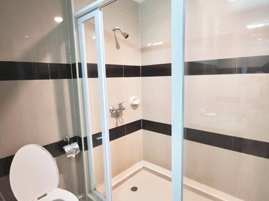 Un baño con inodoro, cabina de ducha y paredes con azulejos.