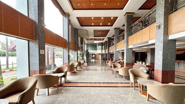 Um hall amplo com tetos altos, grandes janelas e uma variedade de opções de assento, incluindo sofás e cadeiras.