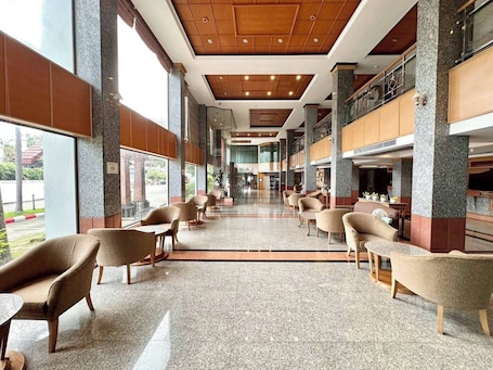 A spacious lobby with high ceilings, large windows, and a mix of seating arrangements including sofas and chairs.