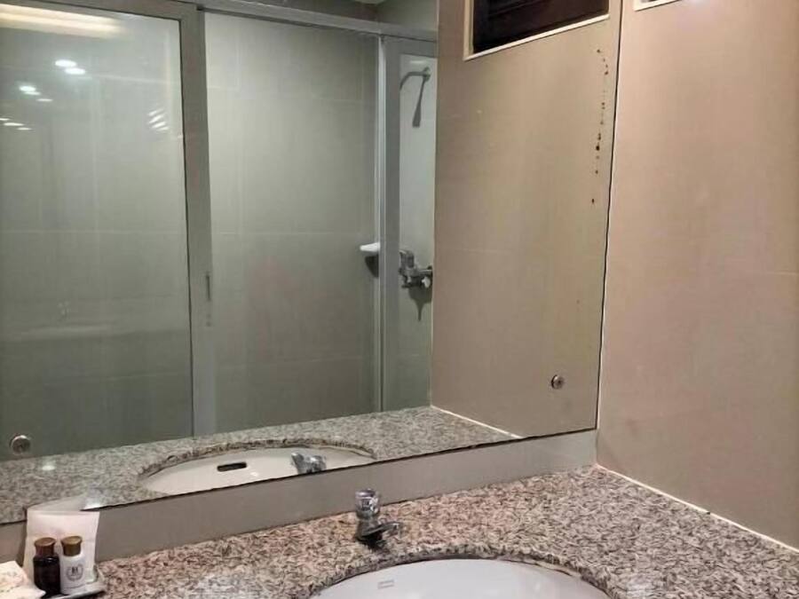 Un baño con lavamanos de encimera de granito, cabina de ducha de vidrio y un espejo.