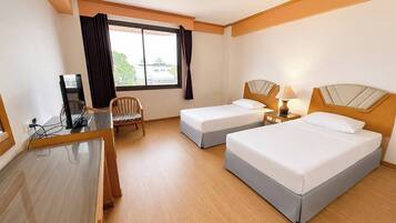 A hotel room with two beds, a desk with a computer, a chair, and a window with curtains.