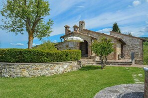 A stone building with a small porch and a tree in the foreground. - Stone house apartment with pool in Tuscan hills (Asciano)