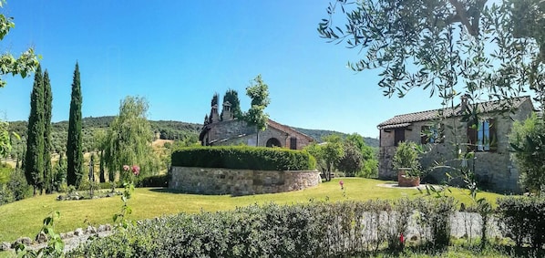 A stone building with a circular garden, a small tower, and a rustic house with a tiled roof. - Stone house apartment with pool in Tuscan hills (Asciano)