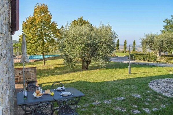 A table set outdoors with a view of a grassy area and trees. - Stone house apartment with pool in Tuscan hills (Asciano)