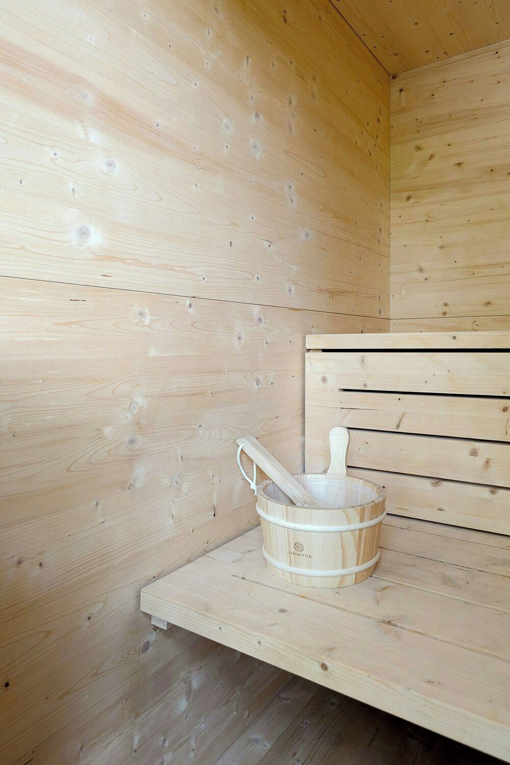 Un sauna en bois, avec un seau en bois et un manche en bois.