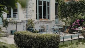 A stone building with a balcony, a small garden with a table and chairs, and a pond. - Charming 1920s house in Picardy, 2h from Paris (Sainte-Croix)