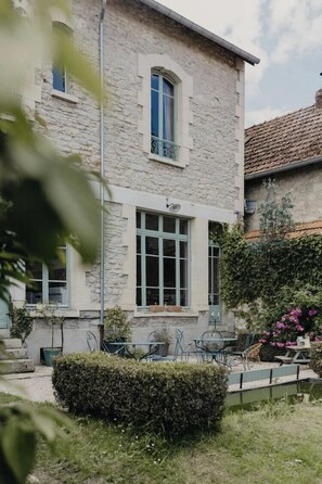 A stone building with a balcony, a small garden with a table and chairs, and a pond. - Charming 1920s house in Picardy, 2h from Paris (Sainte-Croix)