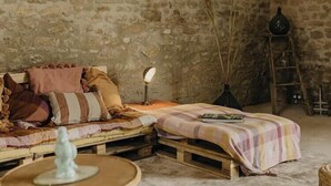 A rustic room with a stone wall, a wooden bed, a small table, and a ladder. - Charming 1920s house in Picardy, 2h from Paris (Sainte-Croix)