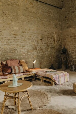 A rustic room with a stone wall, a wooden bed, a small table, and a ladder. - Charming 1920s house in Picardy, 2h from Paris (Sainte-Croix)
