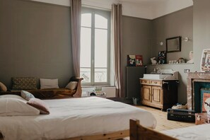 A bedroom with a large bed, a wooden dresser, a radiator, and a window with curtains. - Charming 1920s house in Picardy, 2h from Paris (Sainte-Croix)