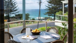 A table with a bowl of lemons, a pitcher, and a glass of water, overlooking a coastal view. - Sandilands 1 - Lifestyle Yamba (YAMBA)