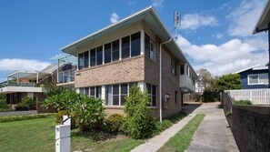 A two-story residential building with a brick facade, large windows, and a covered patio area. - Sandilands 1 - Lifestyle Yamba (YAMBA)