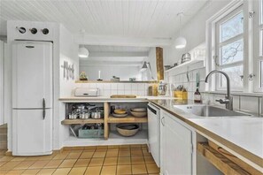 Eine Küche mit weißen Schränken, einem Backofen, einer Spüle und einem Fenster.