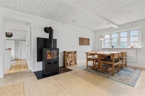 Ein modernes Interieur mit Kamin, Esstisch aus Holz und Stühlen.