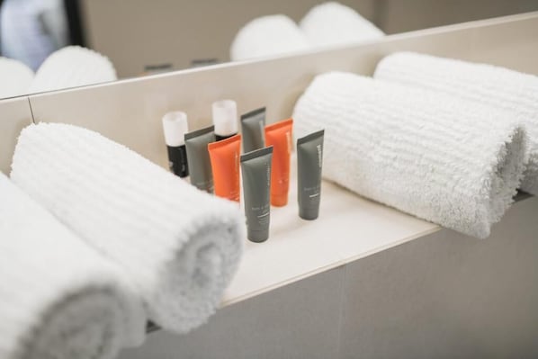 Un baño con toallas, artículos de aseo y un espejo.