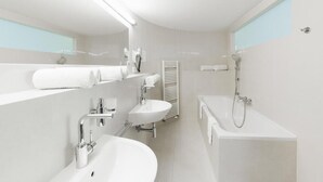 A modern bathroom with a bathtub, a sink, a mirror, and a towel rack.