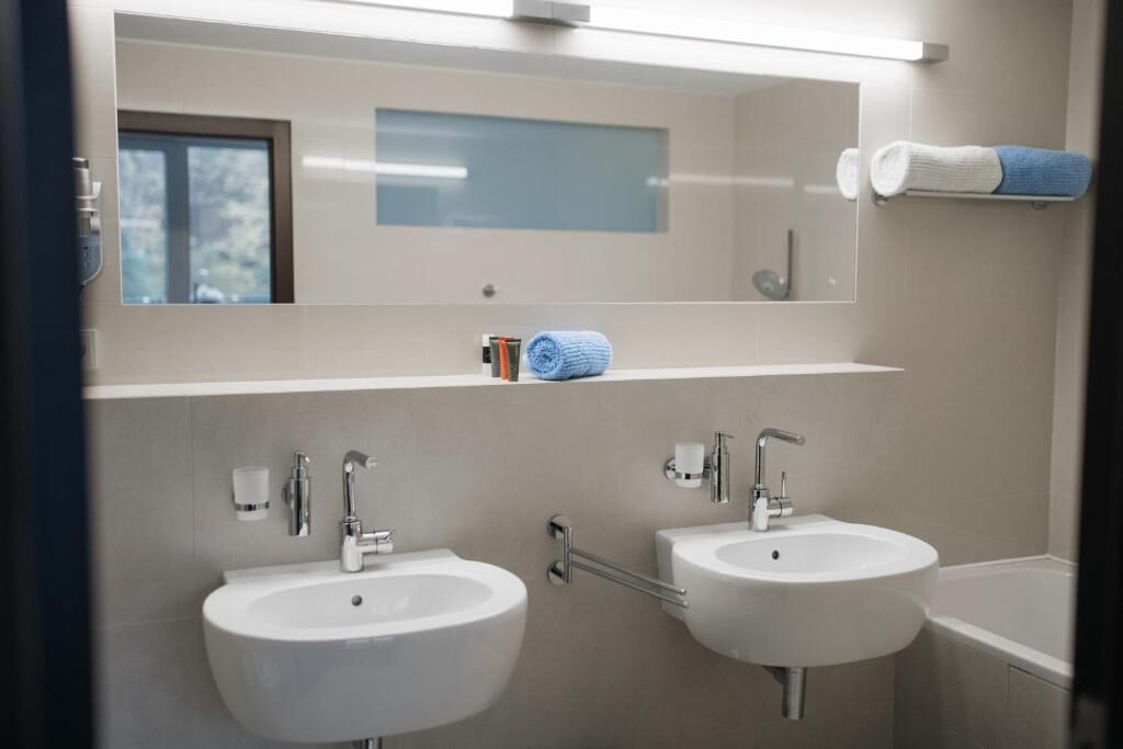 A bathroom with two sinks, a mirror, and a towel rack.