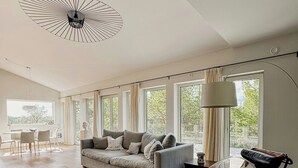 A spacious living room with a sofa, coffee table, and a chair with a leather cushion. - Modern Design Villa on Älgö Island (Saltsjöbaden)