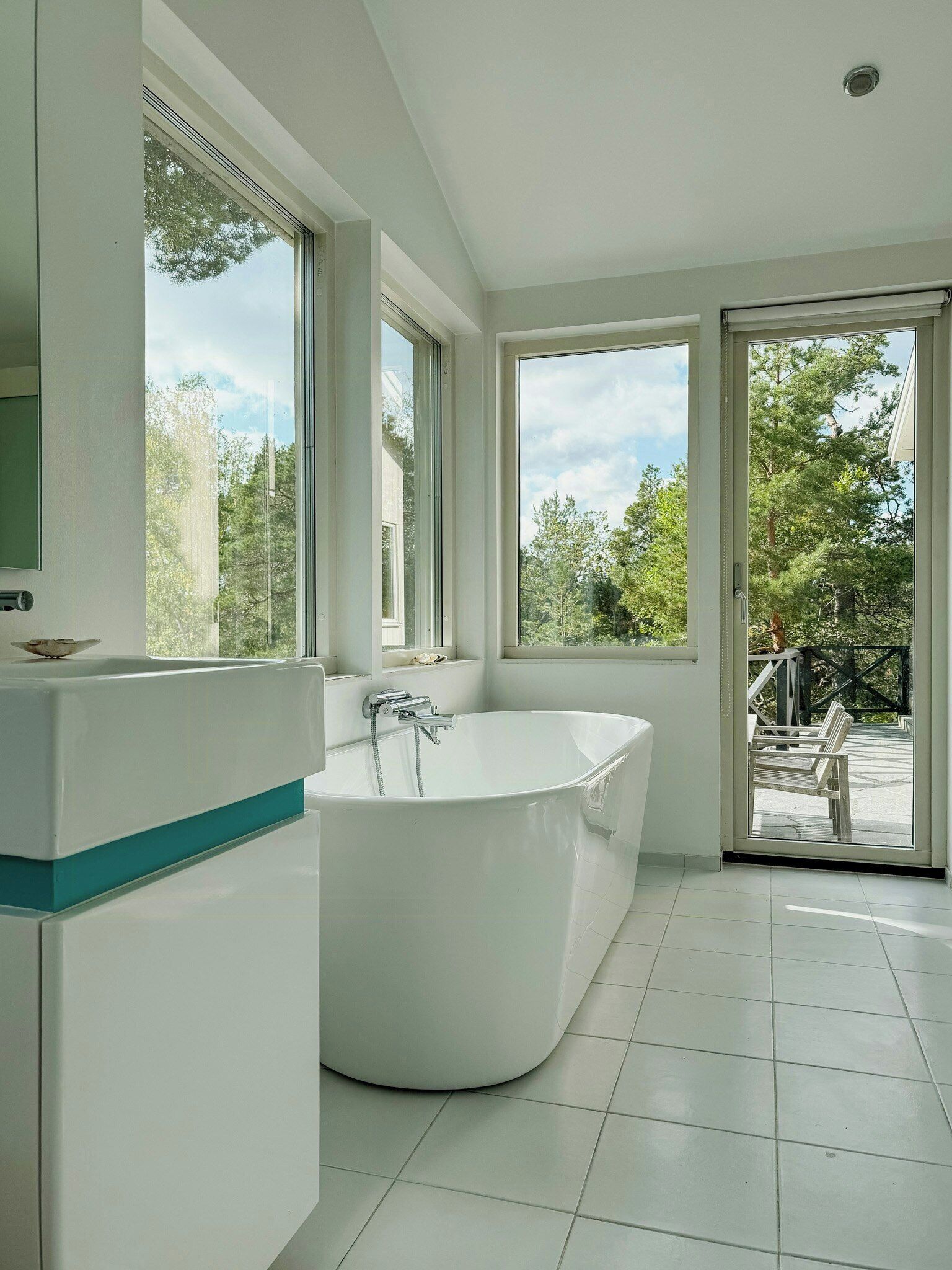 Une salle de bain moderne avec une baignoire sur pieds, de grandes fenêtres et une vue sur l’extérieur.