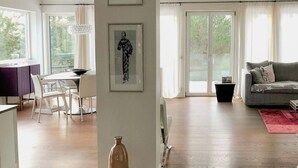 A spacious living area with a dining table, a sofa, and a large window providing natural light. - Modern Design Villa on Älgö Island (Saltsjöbaden)