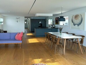 A modern living space with a sofa, dining table, chairs, a kitchen area, and artwork on the walls. - Converted island ferry with sea access in Stege (Stege)